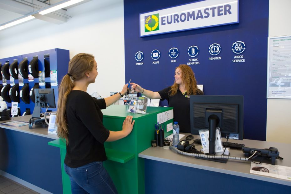 De Assistent Bedrijfsleider bij Euromaster overhandigt de sleutels van een auto aan een klant