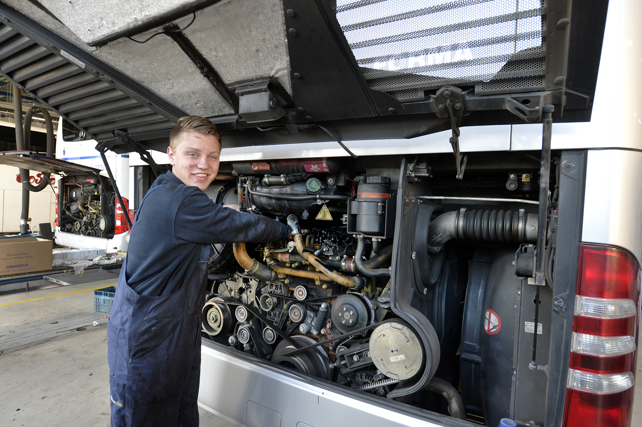 Een Busmonteur / Bedrijfsautotechnicus werkt aan de motor van een bus bij Daimler Buses in Nijkerk.